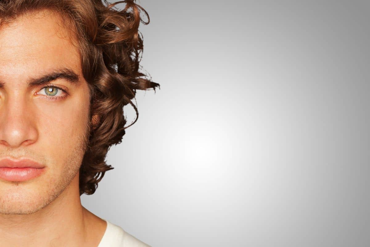 Close-up of young man with defined lips and curly hair highlighting rising trend in male lip lift surgery.